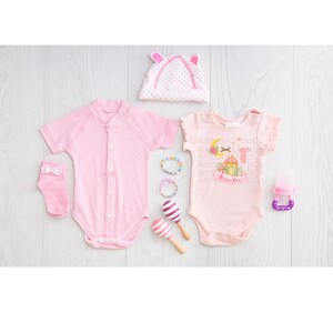 May include: Pink baby clothes set with a pink hat, two pink bodysuits, a pair of pink socks, a set of colorful bracelets, and a pink and purple maraca. One bodysuit has a Ramadan design with the text "Ramadan".