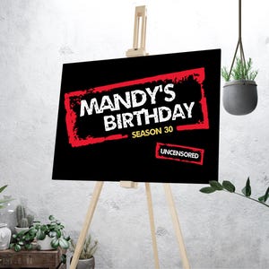 Könnte beinhalten: Ein schwarzes Schild auf einer hölzernen Staffelei mit dem Text "MANDY'S BIRTHDAY SEASON 30" in Weiß, umrahmt von einem roten, verwitterten Rand. Das Wort "UNCENSORED" steht rot am unteren Rand. Das Schild wird in Innenräumen ausgestellt.