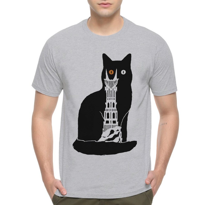 Puede incluir: Una camiseta gris con una silueta de gato negro. El gato tiene un ojo naranja y un ojo blanco. Una torre est&aacute; dentro del cuerpo del gato.