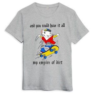 Op de afbeelding: Een grijs T-shirt met een cartoon witte muis die skateboard. De muis draagt een rood shirt, een blauwe jeans en een blauw-witte pet. De tekst op het shirt luidt "and you could have it all my empire of dirt".