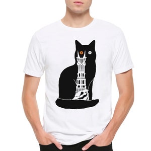 Puede incluir: Camiseta blanca con una silueta negra de un gato con un ojo naranja. El gato sostiene una torre en sus patas.