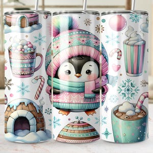 May include: A white tumbler featuring a winter theme with a cute penguin wearing a pink and teal hat and scarf. The design includes snowflakes, igloos, mugs of hot chocolate, and candy canes. The tumbler is approximately 8 inches tall.