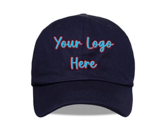 May include: A navy blue baseball cap with the text "Your Logo Here" in a script font with a light blue color and a red outline. The cap is made of a soft material and has a curved brim.