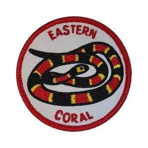 May include: A white embroidered patch with a red border. The patch features a coiled Eastern Coral snake with red, yellow, and black bands. The words "Eastern Coral" are embroidered in red on the patch.