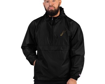 May include: Black anorak jacket with a hood and a front pocket. The jacket has a gold-colored embroidered design on the chest. The jacket is made of a lightweight material and has a Champion logo on the sleeve.