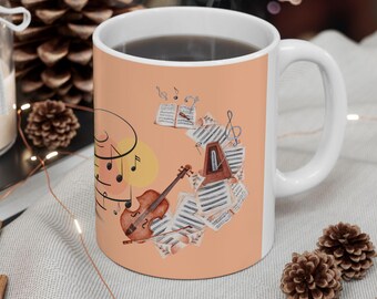 May include: White ceramic mug with a peach-colored background, featuring a watercolor design of musical notes, a violin, and sheet music. The mug has a curved handle and is filled with a dark liquid.