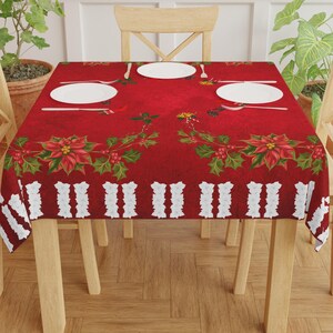 May include: Red and white Christmas tablecloth with a poinsettia and holly design. The tablecloth is laid on a wooden table with four chairs.