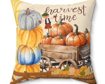 May include: A decorative throw pillow with a watercolor design of pumpkins, a scarecrow, and a wagon. The text "harvest time" is written in brown script on the pillow.