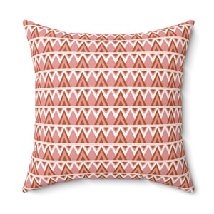 May include: A decorative throw pillow with a geometric pattern of pink and orange triangles on a white background.
