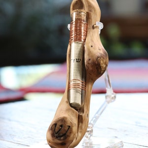 May include: A wooden scroll holder with a glass tube containing a rolled piece of paper with Hebrew writing. The tube is wrapped with copper wire and the holder has a carved Star of David.