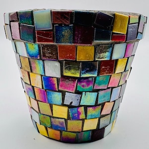 May include: A decorative mosaic flower pot with a concrete base. The pot is covered in iridescent, square tiles in shades of yellow, pink, blue, and green. The mosaic design adds a unique, colorful touch to the garden decor.