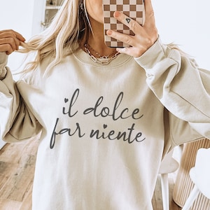 K&ouml;nnte beinhalten: Ein hellbeiger Pullover mit dem Aufdruck "il dolce far niente" in Schwarz.