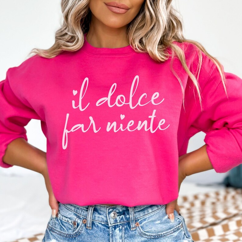 K&ouml;nnte beinhalten: Ein rosa Sweatshirt mit dem Text "il dolce far niente" in wei&szlig;er Schrift mit einem kleinen Herzen &uuml;ber dem Wort "far".