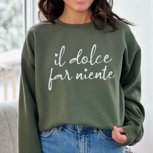 K&ouml;nnte beinhalten: Ein gr&uuml;ner Pullover mit dem Text "il dolce far niente" in wei&szlig;en Buchstaben.
