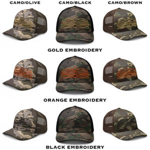 May include: A collection of camouflage baseball caps with mesh backs. The caps feature various embroidery colors, including gold, orange, and black, and are labeled with color combinations like Camo/Olive and Camo/Black. The caps are designed for outdoor wear.