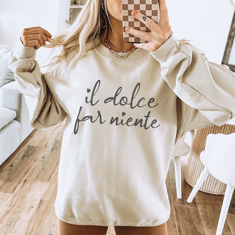 K&ouml;nnte beinhalten: Ein hellbeiger Pullover mit dem Aufdruck "il dolce far niente" in Schwarz.