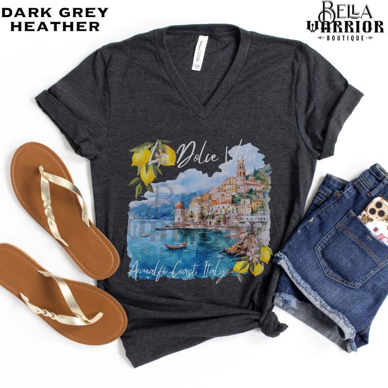 May include: Dark grey heather V-neck t-shirt with a watercolour illustration of a coastal Italian town with the text "La Dolce Vita Amalfi Coast Italy".