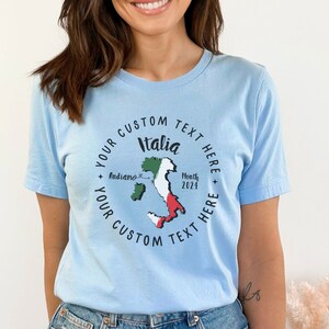K&ouml;nnte beinhalten: Hellblaues T-Shirt mit einem kreisf&ouml;rmigen Design. Das Design zeigt das Wort "Italia" und eine Karte von Italien in Gr&uuml;n, Wei&szlig; und Rot. Das Design enth&auml;lt den Text "Your Custom Text Here" und "Month 2024".