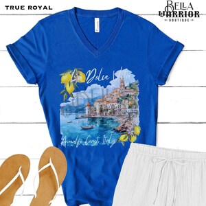 May include: A royal blue v-neck t-shirt featuring a watercolour image of a coastal town with the text "La Dolce Vita Amalfi Coast Italy".