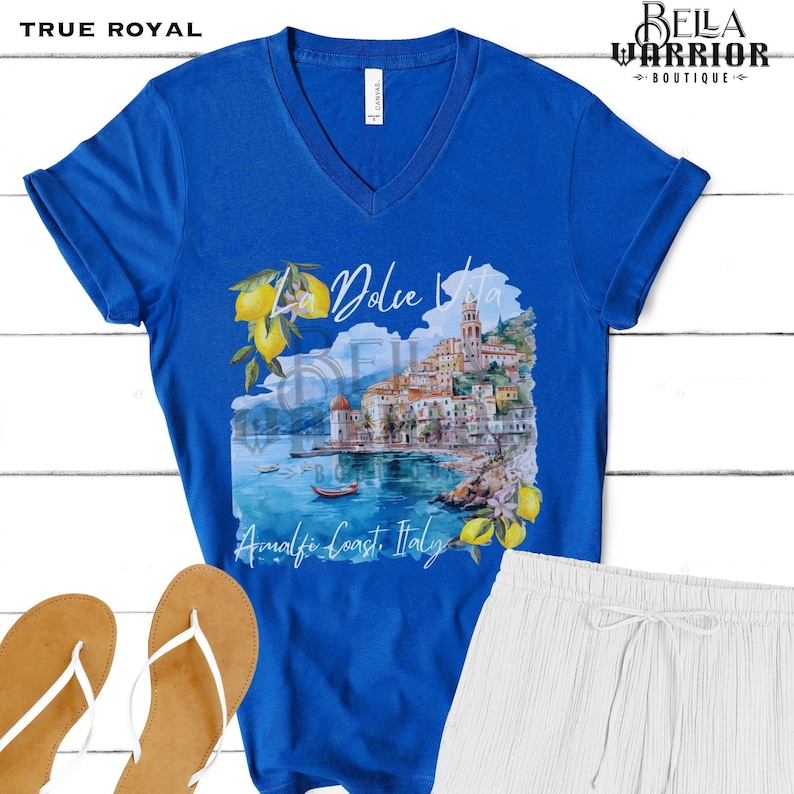 May include: A royal blue v-neck t-shirt featuring a watercolour image of a coastal town with the text "La Dolce Vita Amalfi Coast Italy".
