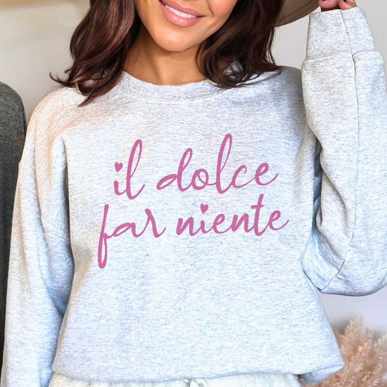 K&ouml;nnte beinhalten: Grauer Pullover mit dem Schriftzug "il dolce far niente" in rosa mit kleinen Herzen.