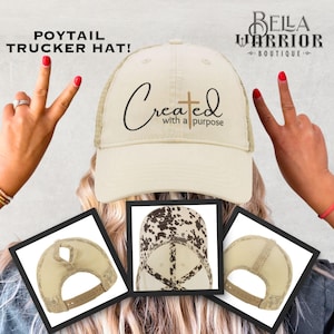 May include: Cream-colored trucker hat with a mesh back and a curved brim. The hat features the text "Created with a purpose" and a cross graphic. The image also shows two additional hat designs and the words "POYTAIL TRUCKER HAT!"
