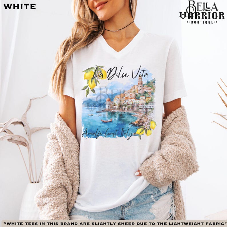 May include: White V-neck t-shirt featuring a watercolour illustration of a coastal Italian town with the text "La Dolce Vita" and "Amalfi Coast, Italy".