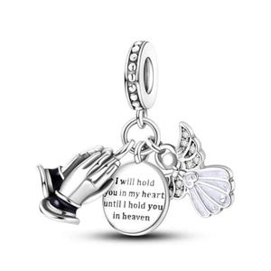 Può includere: Charm in argento con mani in preghiera, un'ala d'angelo e un ciondolo circolare. Il ciondolo recita: "Ti terrò nel mio cuore finché non ti terrò in cielo."