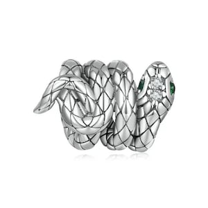 May include: A silver snake charm with green and clear gemstones. The snake is coiled and has a detailed textured surface.