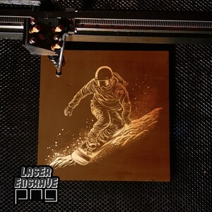 Puede incluir: Una placa de madera grabada con l&aacute;ser con un dise&ntilde;o de un snowboarder con casco y gafas, bajando por una ladera nevada. La placa tiene un fondo marr&oacute;n y el dise&ntilde;o es de color marr&oacute;n claro. El texto "LASER ENGRAVE" es visible en la esquina inferior izquierda de la placa.