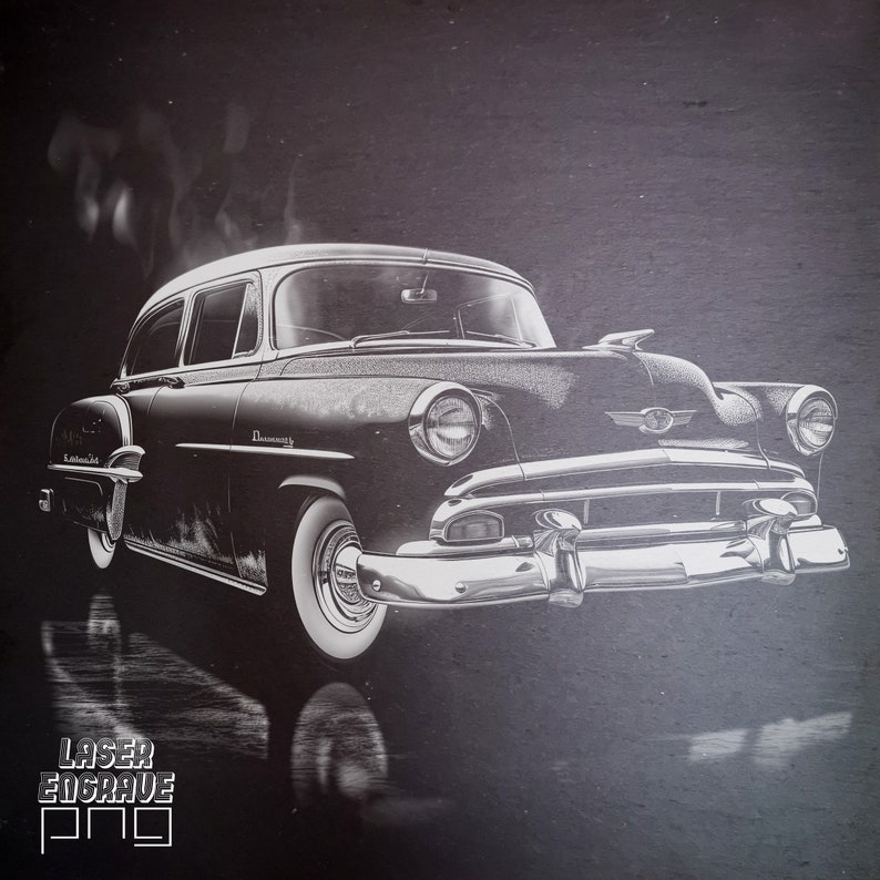 May include: A black and white vintage car with a chrome bumper and headlights. The car is on a dark background with a grainy texture. The word "LASER ENGRAVE" is printed in the bottom left corner of the image.