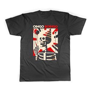 Op de afbeelding: Zwart T-shirt met een afbeelding van een skelet dat een feestmuts draagt en een sigaret vasthoudt. De tekst "Oingo Boingo" is boven de afbeelding gedrukt.