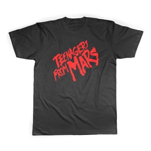 Puede incluir: Camiseta negra con un estampado gráfico rojo que dice "Teenagers from Mars".