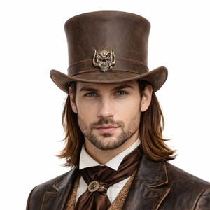 Può includere: Un cappello a cilindro in pelle marrone con un'emblema a teschio sulla fascia. Il cappello ha una corona alta e cilindrica e un'ampia tesa. Fa parte di un ensemble di ispirazione steampunk o vittoriana.