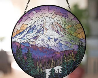 May include: A stained glass window hanging with a depiction of a snow-capped mountain with a purple, blue, and green forest in the foreground.