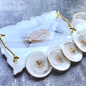 May include: White resin serving tray with gold leaf accents and a gold twig handle. The tray is accompanied by four white resin coasters with gold leaf accents.