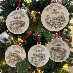 May include: Four round wooden ornaments with red string hangers. Each ornament features a detailed line drawing of a car engine with the text "LS1", "LS3", "LS7", and "LSA" on each ornament.