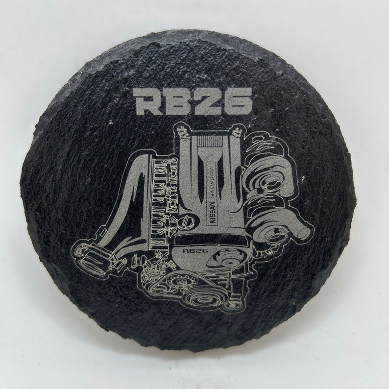 May include: Black slate coaster with a silver engraving of a Nissan RB26 engine. The engine is depicted in detail, with the text "RB26" and "NISSAN" visible.