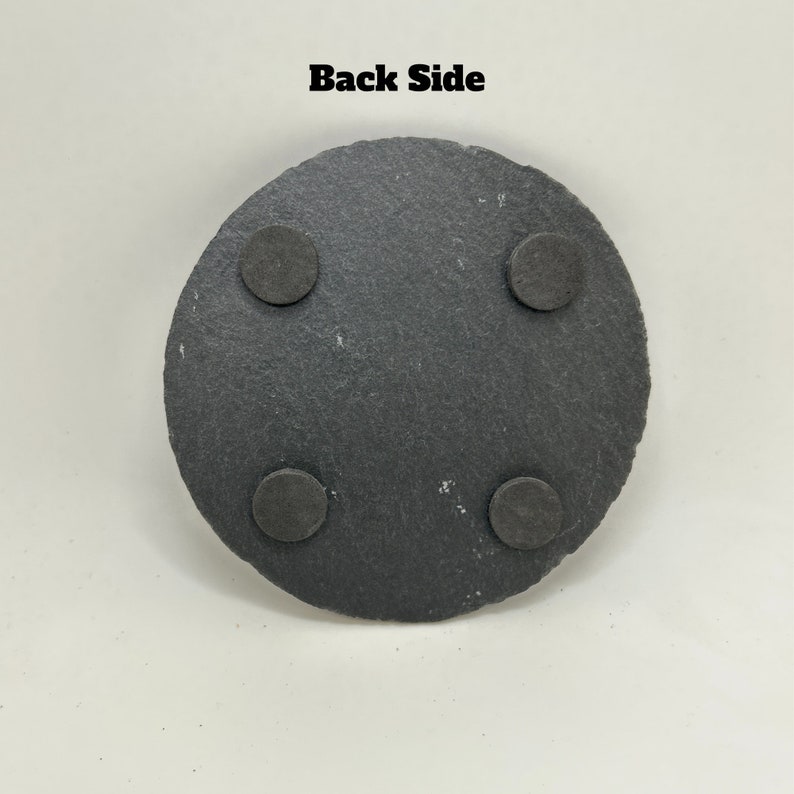 May include: Black round slate coaster with four black felt pads on the bottom. "Back Side" is written in black text at the top of the image.
