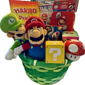 Pu&ograve; includere: Un cesto verde pieno di regali a tema Super Mario Bros., tra cui peluche di Mario e Luigi, un kit di attivit&agrave; con adesivi, un dispenser di caramelle, un blocco con punto interrogativo e un fungo rosso.