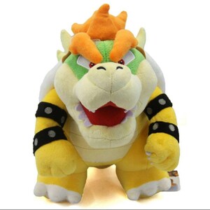 Pu&ograve; includere: Un peluche giallo e verde di Bowser, un personaggio della serie di videogiochi Super Mario. Bowser ha una corona arancione a punta e un'espressione feroce.