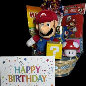 Pu&ograve; includere: Un cesto di vimini pieno di un set regalo di compleanno a tema Mario. Il set include un giocattolo di peluche Mario, un fungo rosso e bianco, un blocco con punto interrogativo, un kit di attivit&agrave; con adesivi, una tazza rossa con un design di Mario e un biglietto che dice "Buon compleanno".