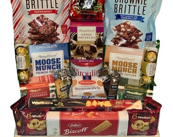 May include: A wicker basket filled with a variety of sweet treats, including chocolate truffles, brownie brittle, popcorn, shortbread cookies, and stroopwafels. The basket is decorated with red and green ribbon and a festive bow.
