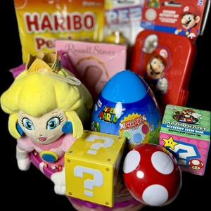 Pu&ograve; includere: Un cestino rosa con un peluche rosa e giallo della principessa Peach, un uovo blu di Super Mario, un blocco giallo con un punto interrogativo, un fungo rosso e bianco e una scatola di caramelle di Mario Kart.