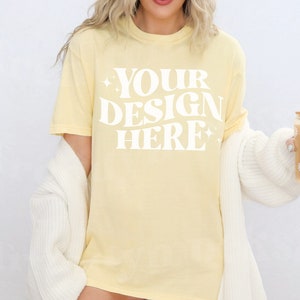 May include: A pale yellow t-shirt with the text 'YOUR DESIGN HERE' in white. The text is in a retro font style with stars on either side.