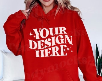 Könnte beinhalten: Ein roter Kapuzenpullover mit Kordelzugkapuze und Vordertasche. Der Kapuzenpullover trägt den Text "YOUR DESIGN HERE" in einer weißen, stilisierten Schriftart. Das Bild ist ein Produkt-Mockup.