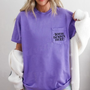 May include: A purple t-shirt with a pocket on the left side. The pocket has the text "YOUR DESIGN HERE" printed on it.