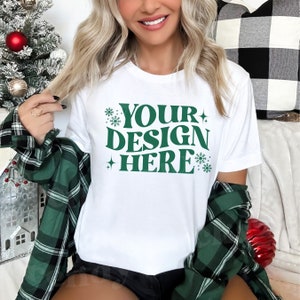May include: White t-shirt with a green design that says "YOUR DESIGN HERE" with snowflakes and stars around the text.