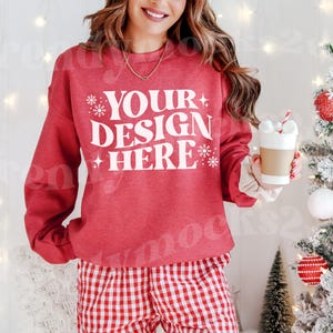 May include: Red sweatshirt with white text that says "YOUR DESIGN HERE" with snowflake accents. The model is wearing red and white checkered pants.