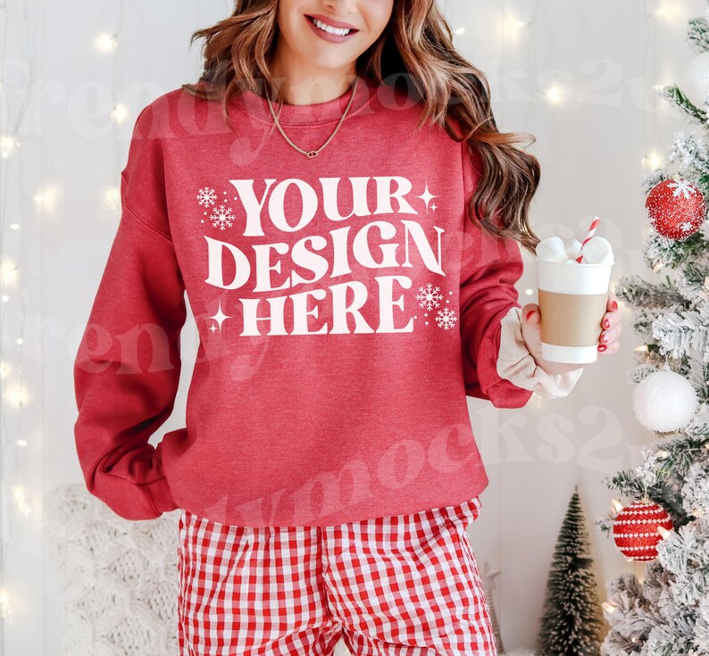 May include: Red sweatshirt with white text that says "YOUR DESIGN HERE" with snowflake accents. The model is wearing red and white checkered pants.